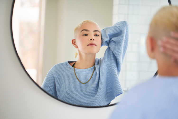 woman looking into mirror after prescription sknicare with wisp