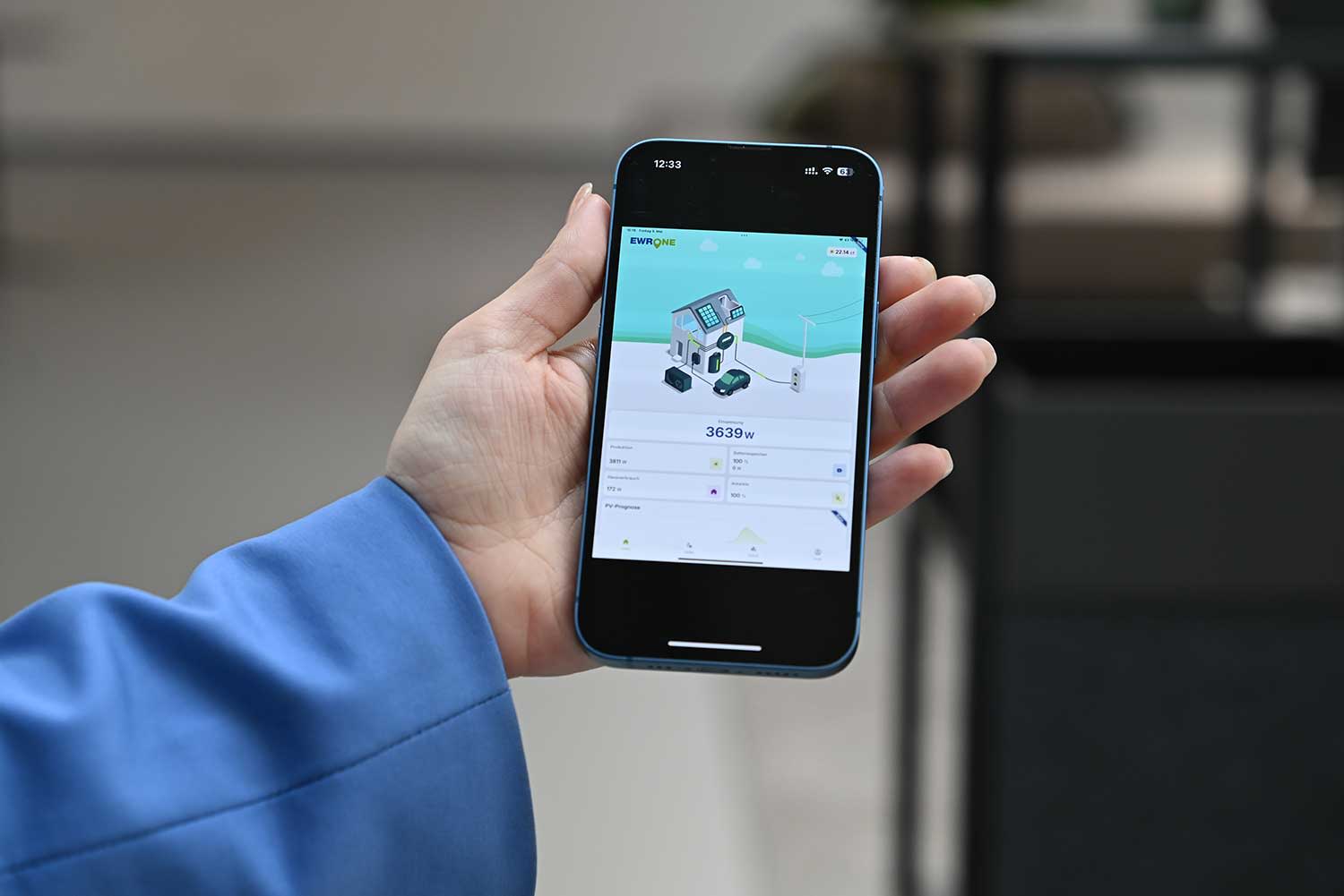 Titelbild Hand mit Handy auf dem der EWR One Manager angezeigt wird.