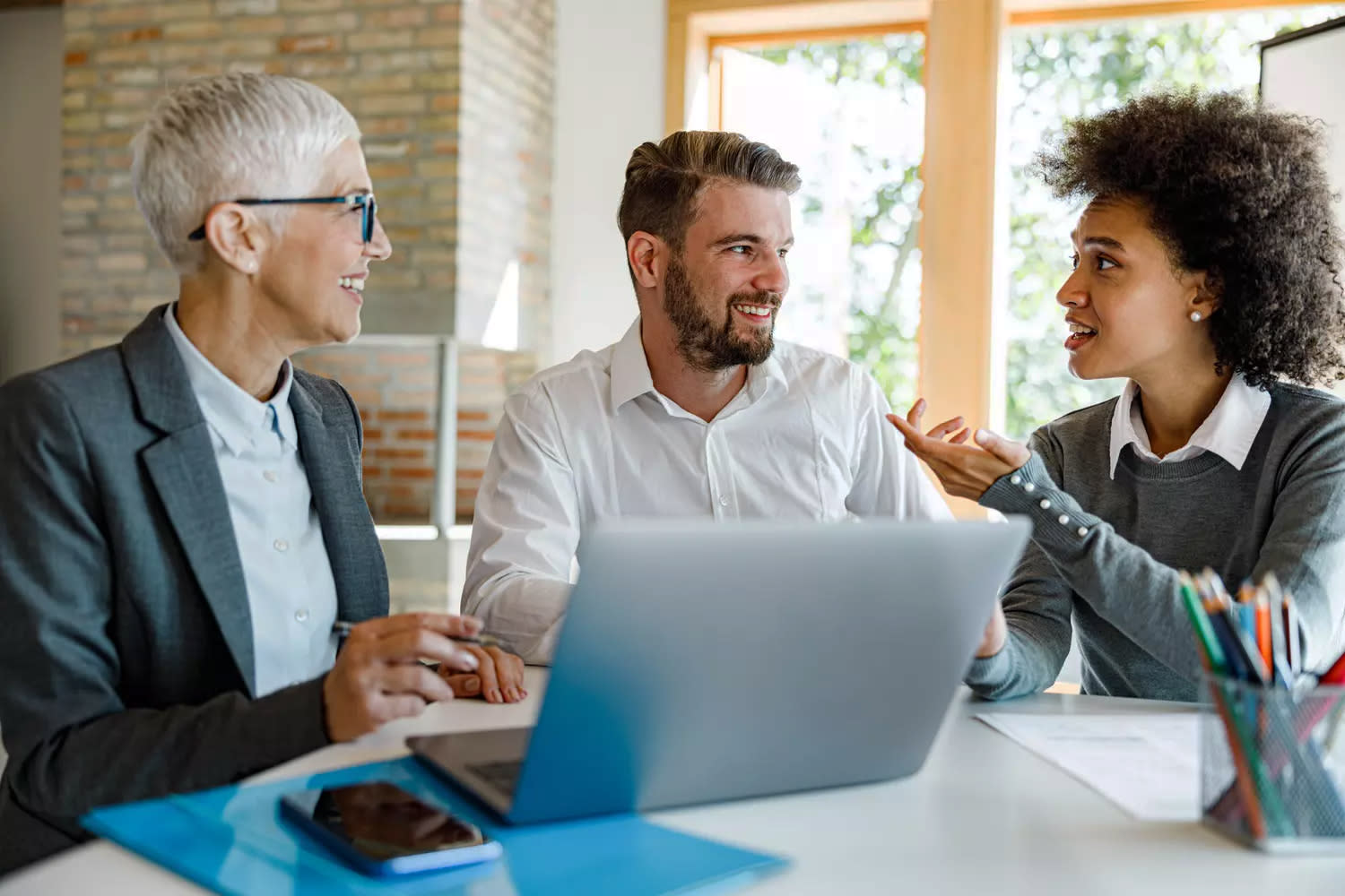 Drei Personen sprechen am Laptop.
