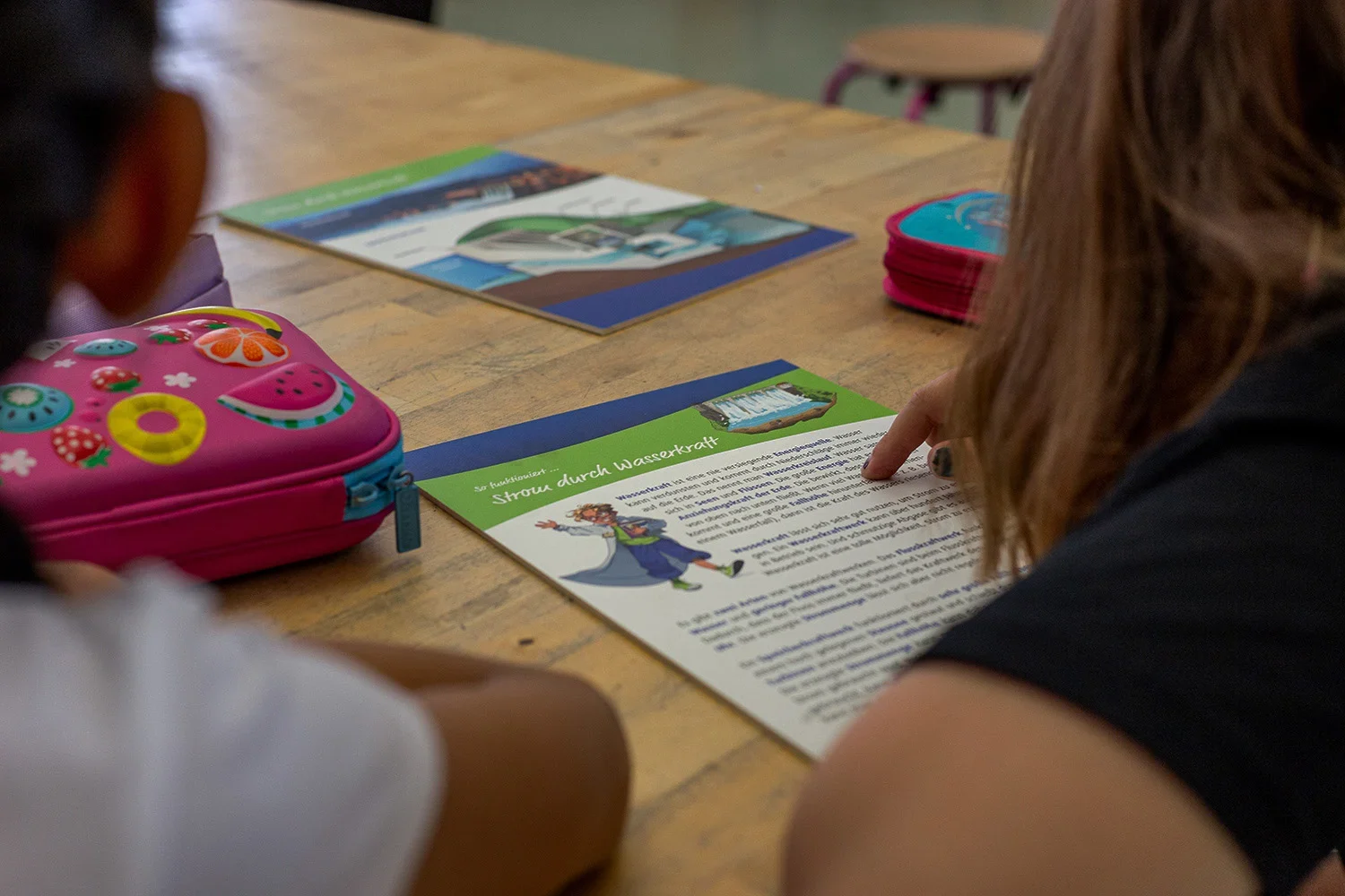 Kinder sitzen am Tisch mit Unterlagen des EWR Enerigesparführerschein