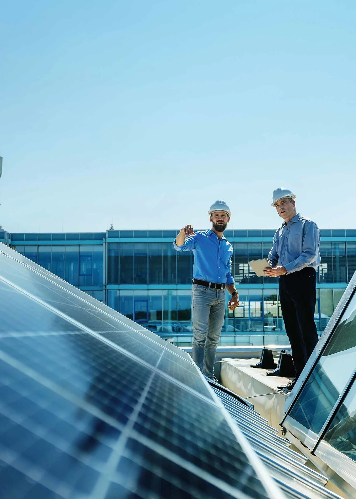 Handwerker auf einem Dach betrachten eine Photovoltaikanlage