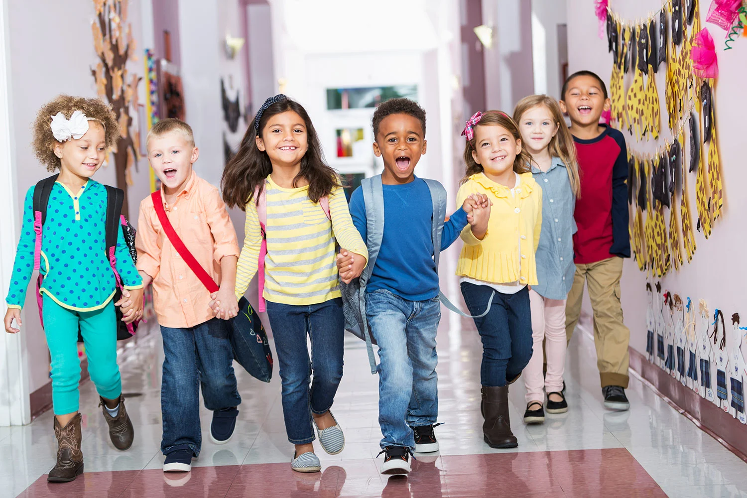 Gruppe von Kindern die Hand in Hand im Flur entlang läuft