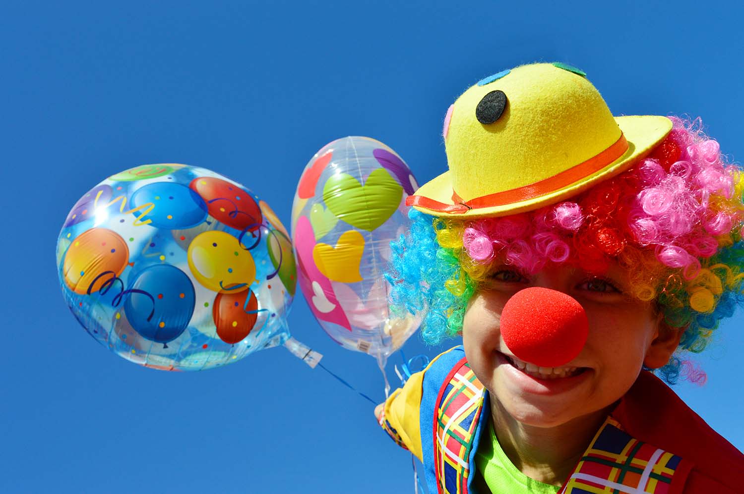 Kind als Clown verkleidet mit Luftabllons, Hut und roter Nase Kind als Clown verkleidet mit Luftabllons, Hut und roter Nase