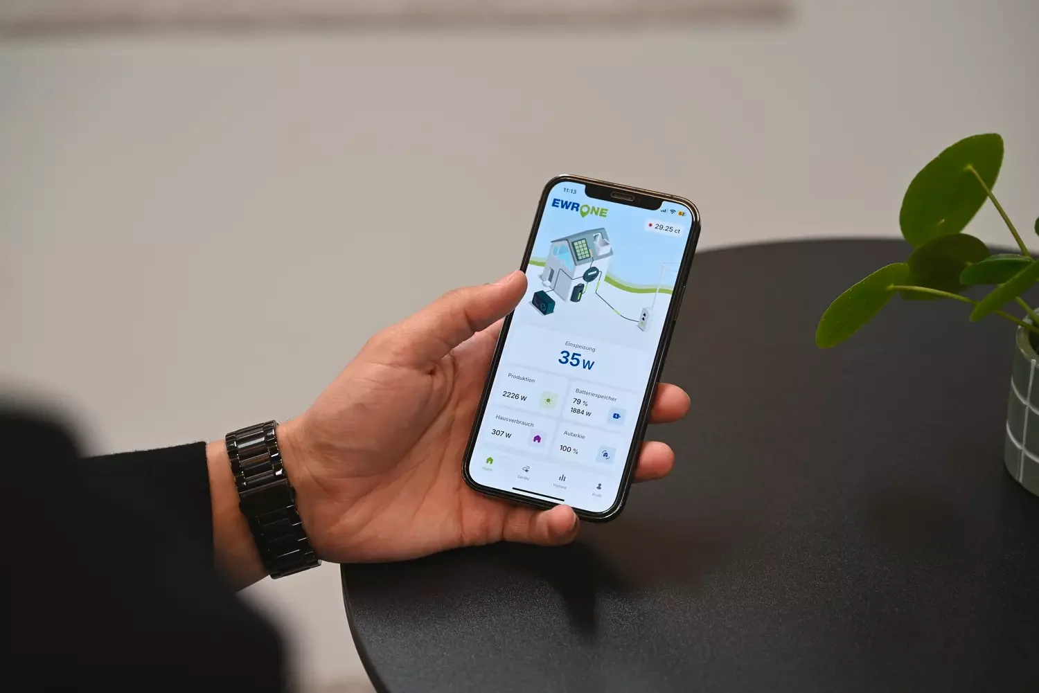 Männliche Hand mit Handy und dem EWR One Manager darauf.