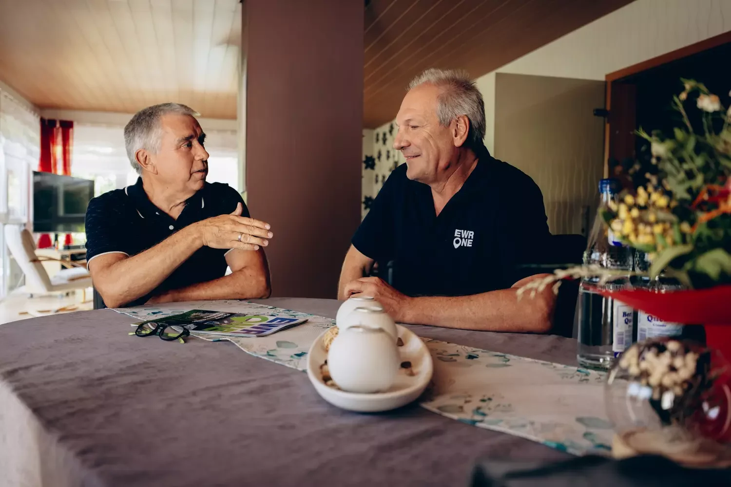 Berater mit Kunde am Tisch im Wohnzimmer.