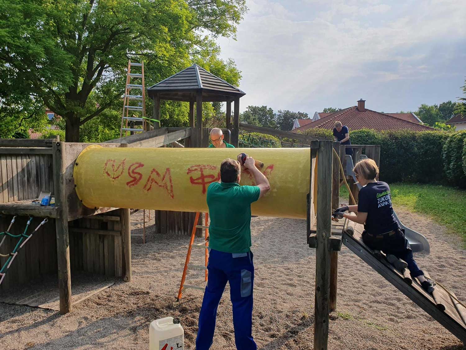 EWR-Helfer schleift Grafiti-Schmiererei von einem Spielplatzgerät ab.