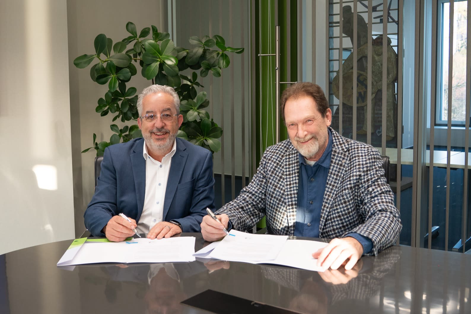 Zwei Männer sitzen an einem Tisch und unterzeichnen einen Vertrag