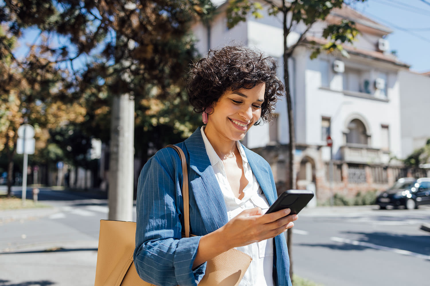 Eine Frau, die auf ihrem Smartphone SMS schreibt, während sie durch die Stadt geht