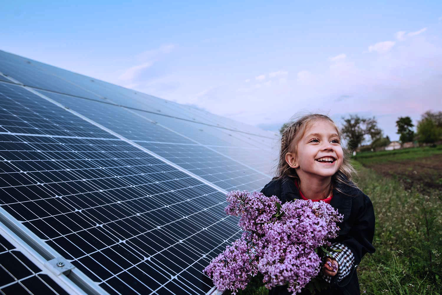 Titelbild Ein Mädchen hält Blumen vor einer Photovoltaikanlage