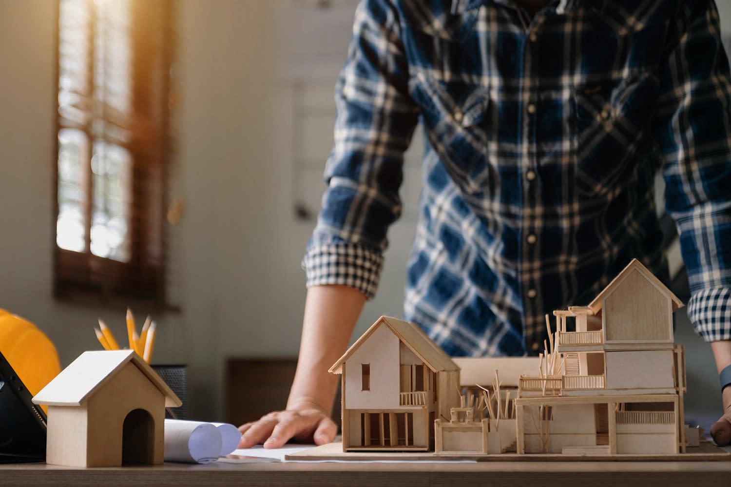 Ein Mann steht an einem Tisch vor einem Hausmodell