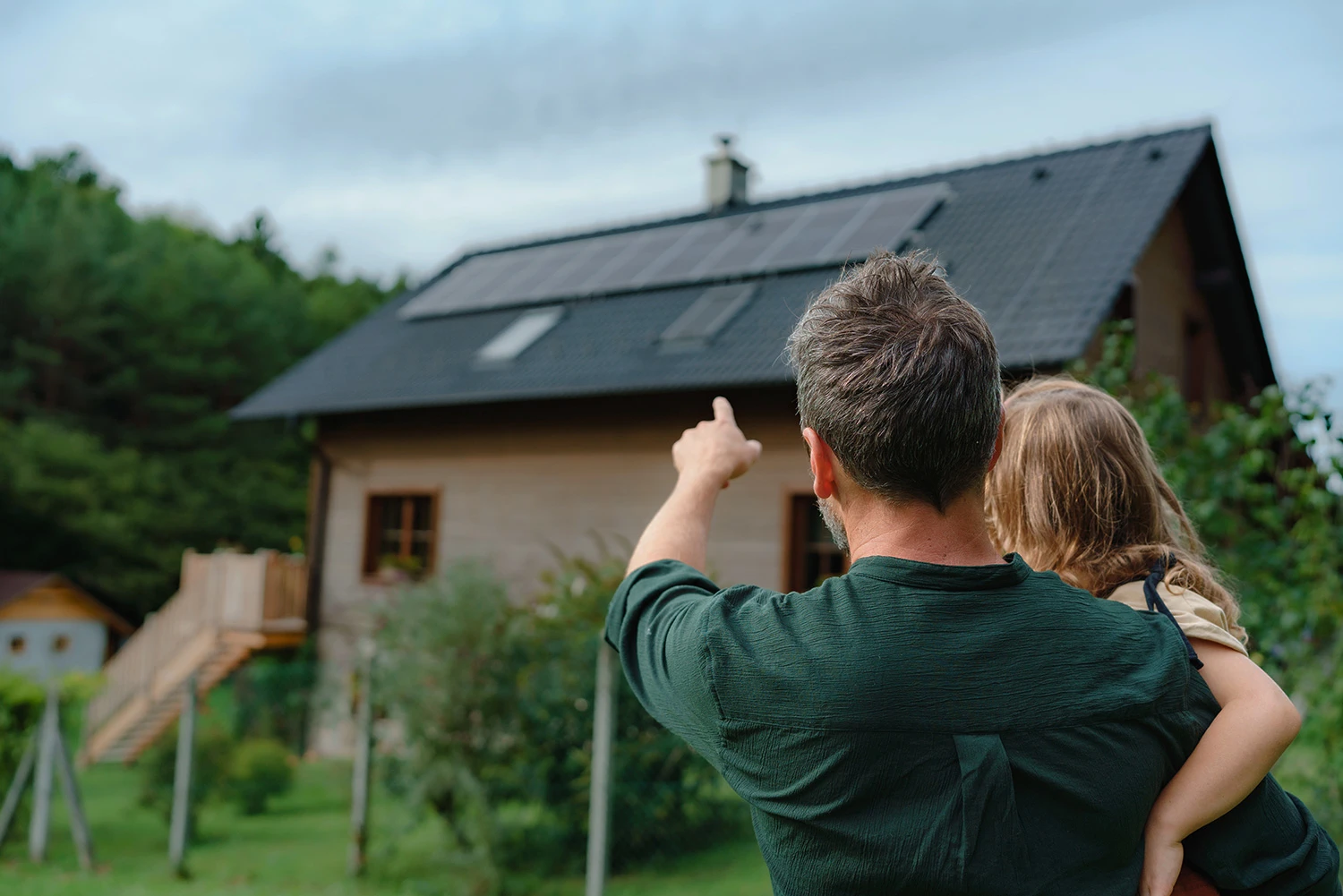 Papa zeigt Tochter Haus mit installierten Sonnenkollektoren zeigt.