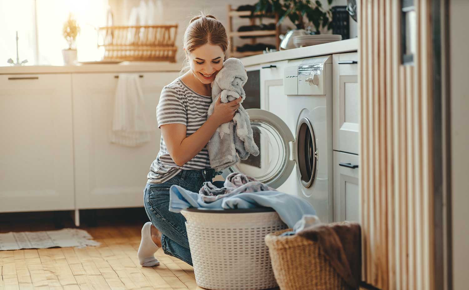 Glückliche Frau in der Waschküche befüllt die Waschmaschine