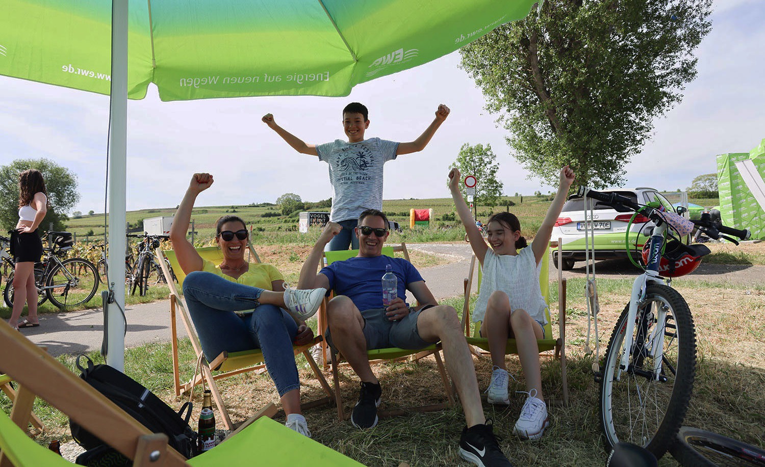 Fröhliche Familie sitzt beim Rheinradeln unter Sonnenschirm