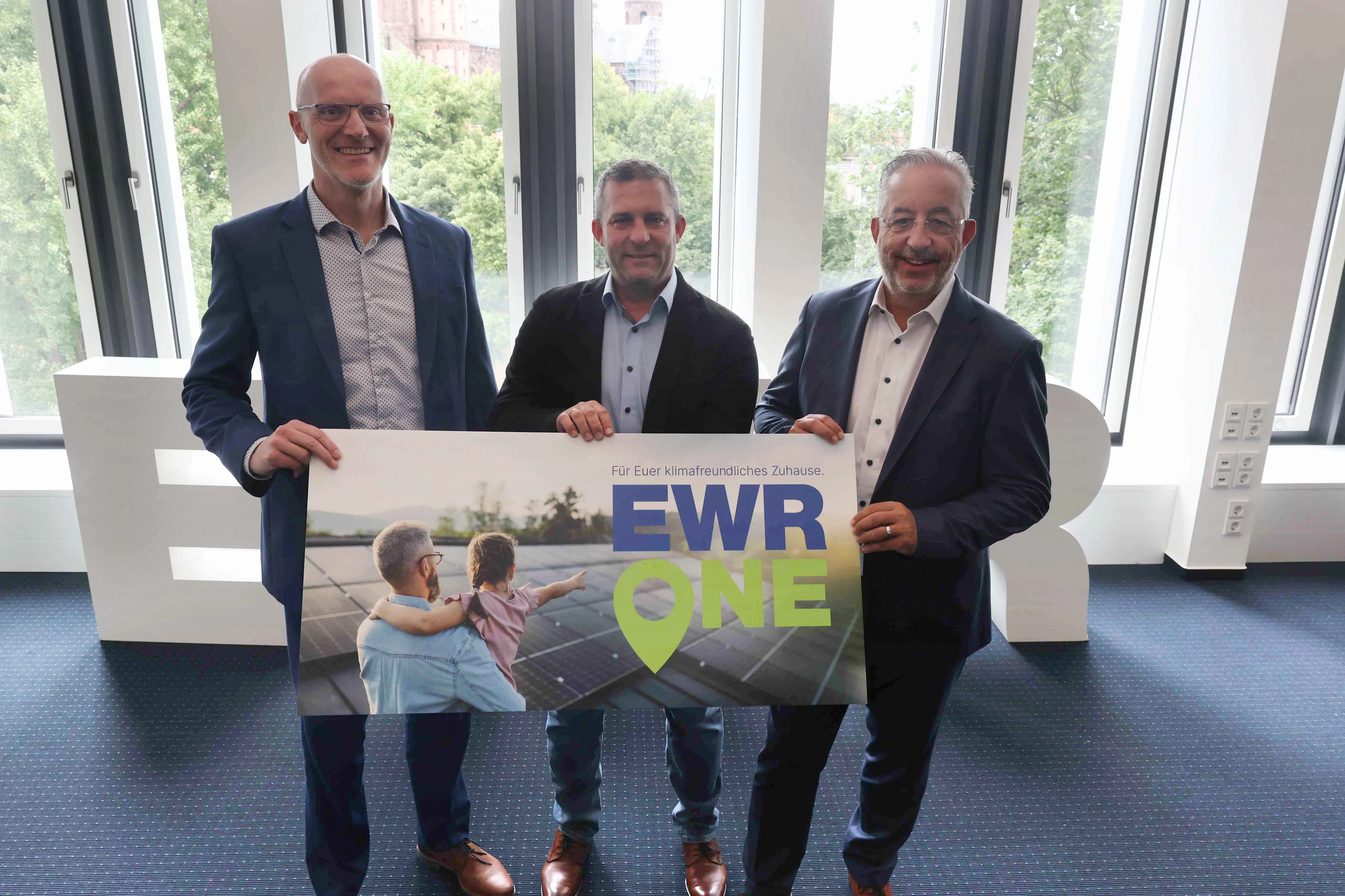 Titelbild Dieter Lagois, Ronnie Schrinner und Stephan Wilhelm halten gemeinsam ein Schild, auf dem EWR One steht.