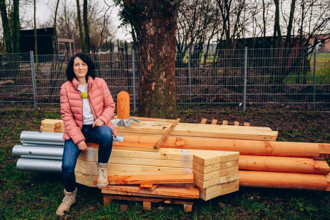Corina Wilding vom Förderverein der Kita Morgenstern sitzt im Garten auf Holzbalken.