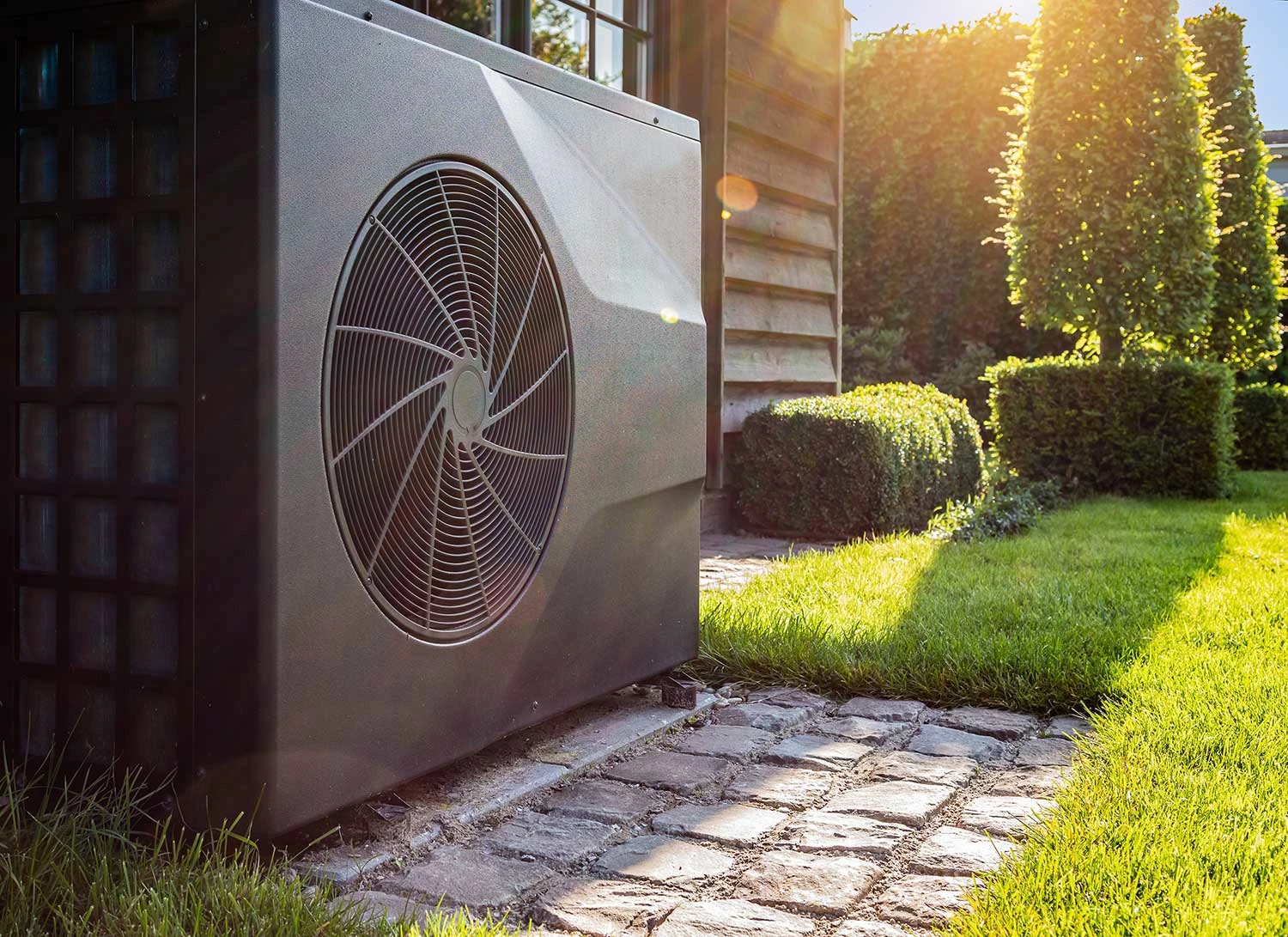 Wärmepumpe steht im Garten an Hauswand