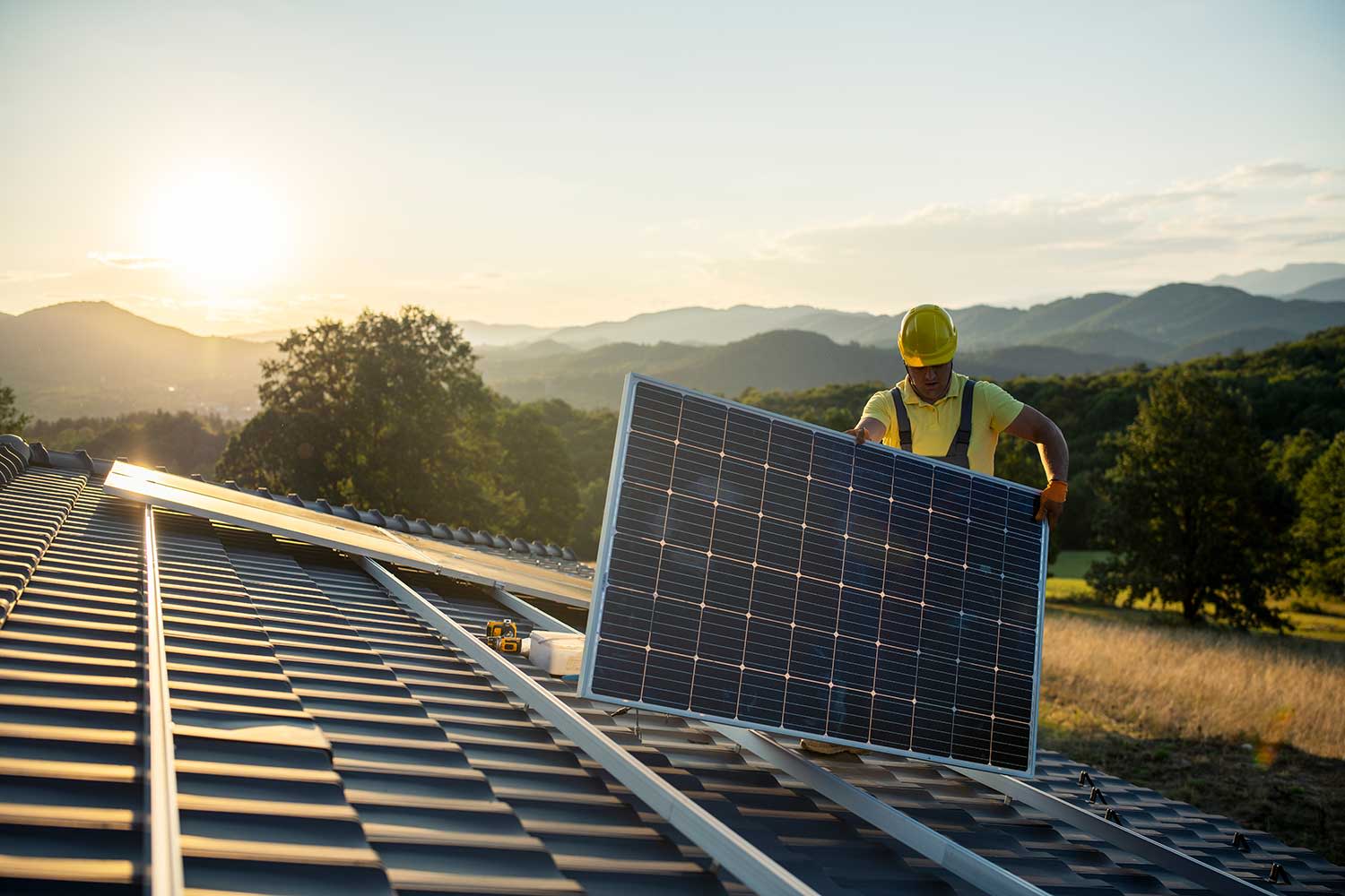 Techniker montiert Sonnenkollektoren auf ein Hausdach