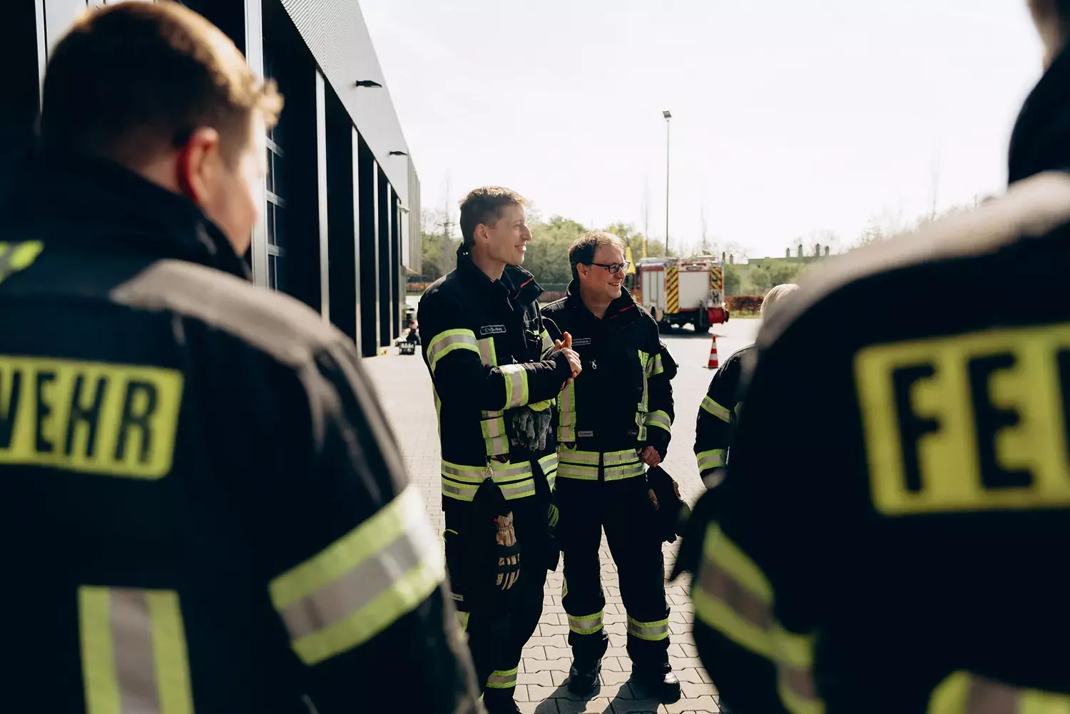 Feuerwehrleute stehen fröhlich vor Gebäude