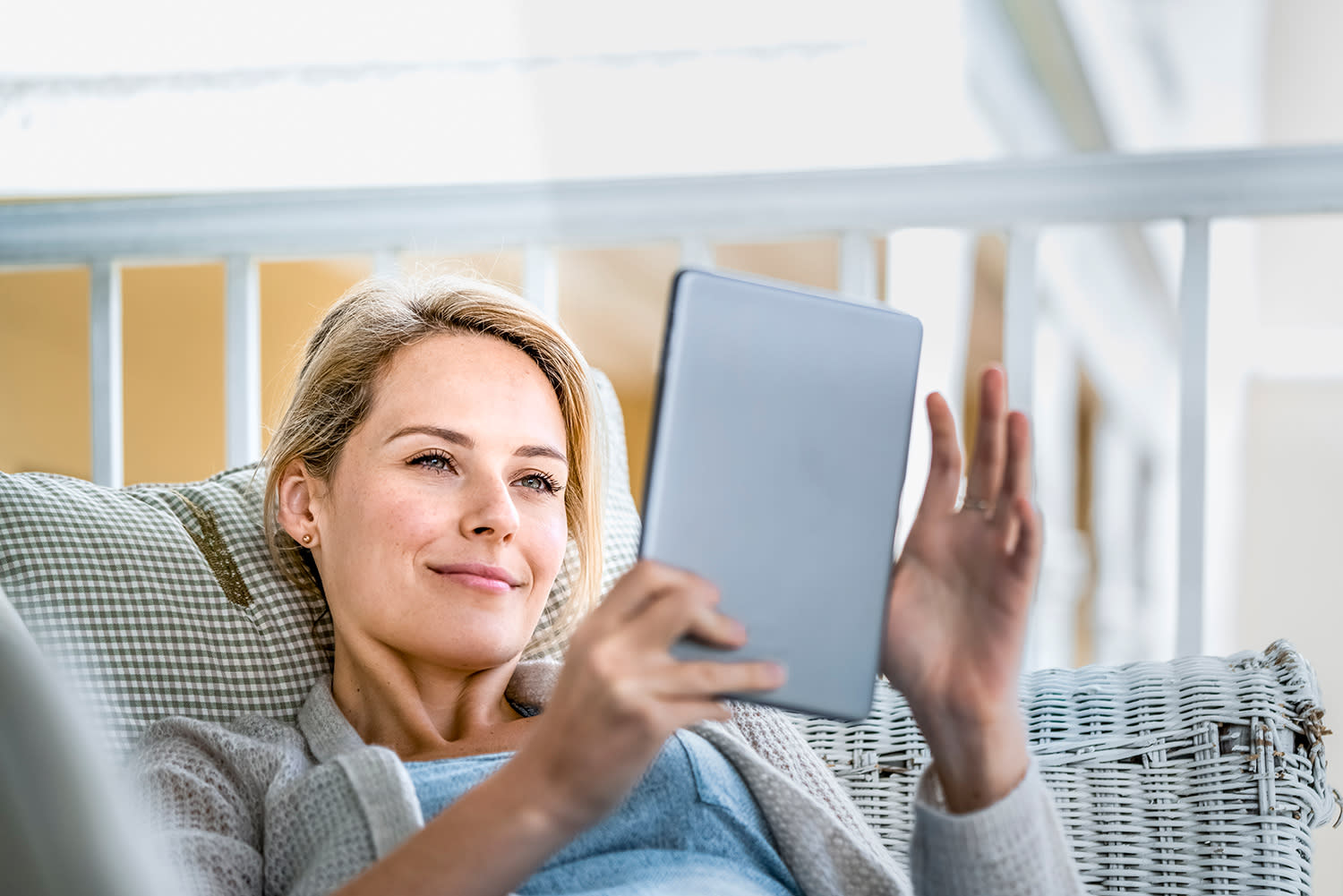 Frau liegt mit Tablet auf Balkon'