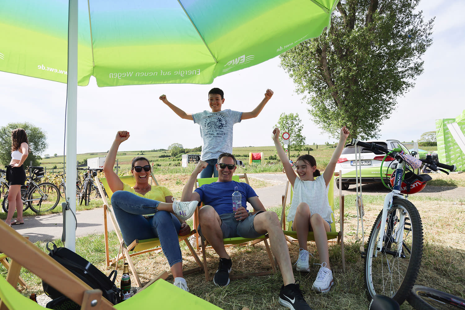 Fröhliche Familie sitzt beim Rheinradeln unter Sonnenschirm