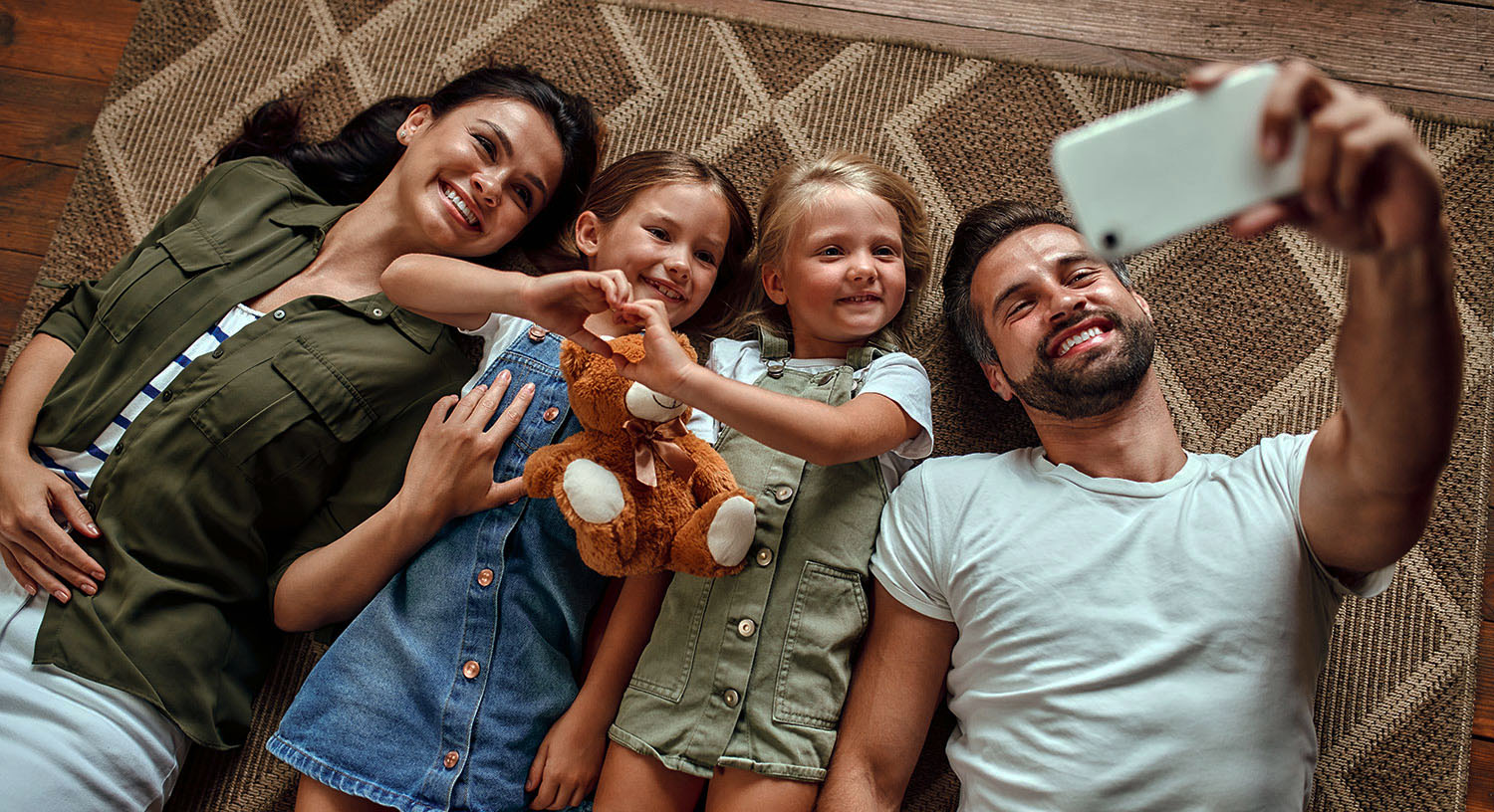 Familie liegt auf Boden und schaut auf ein Smartphone