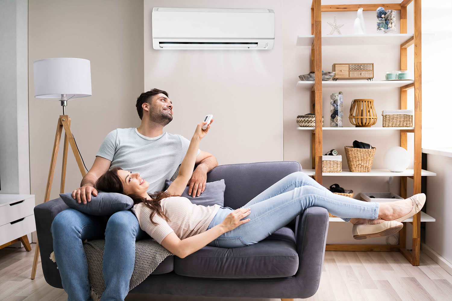 Ein junges Paar sitzt entspannt unter der Klimaanlage auf der Couch