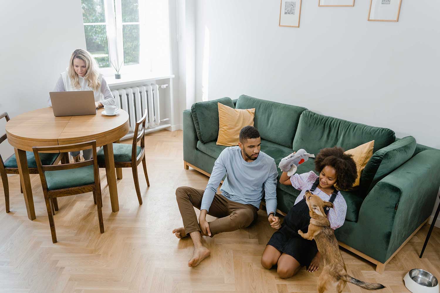 Familie mit Hund sitzt im Wohnzimmer vor der Couch