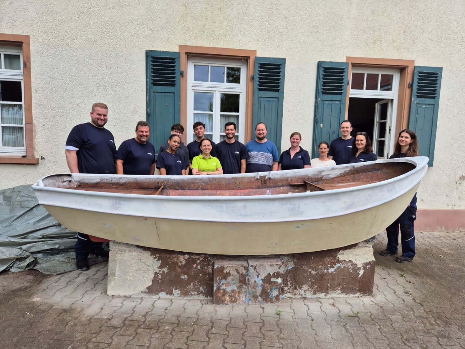 EWR-Mitarbeitende stehen vor einem unbestrichenen Boot