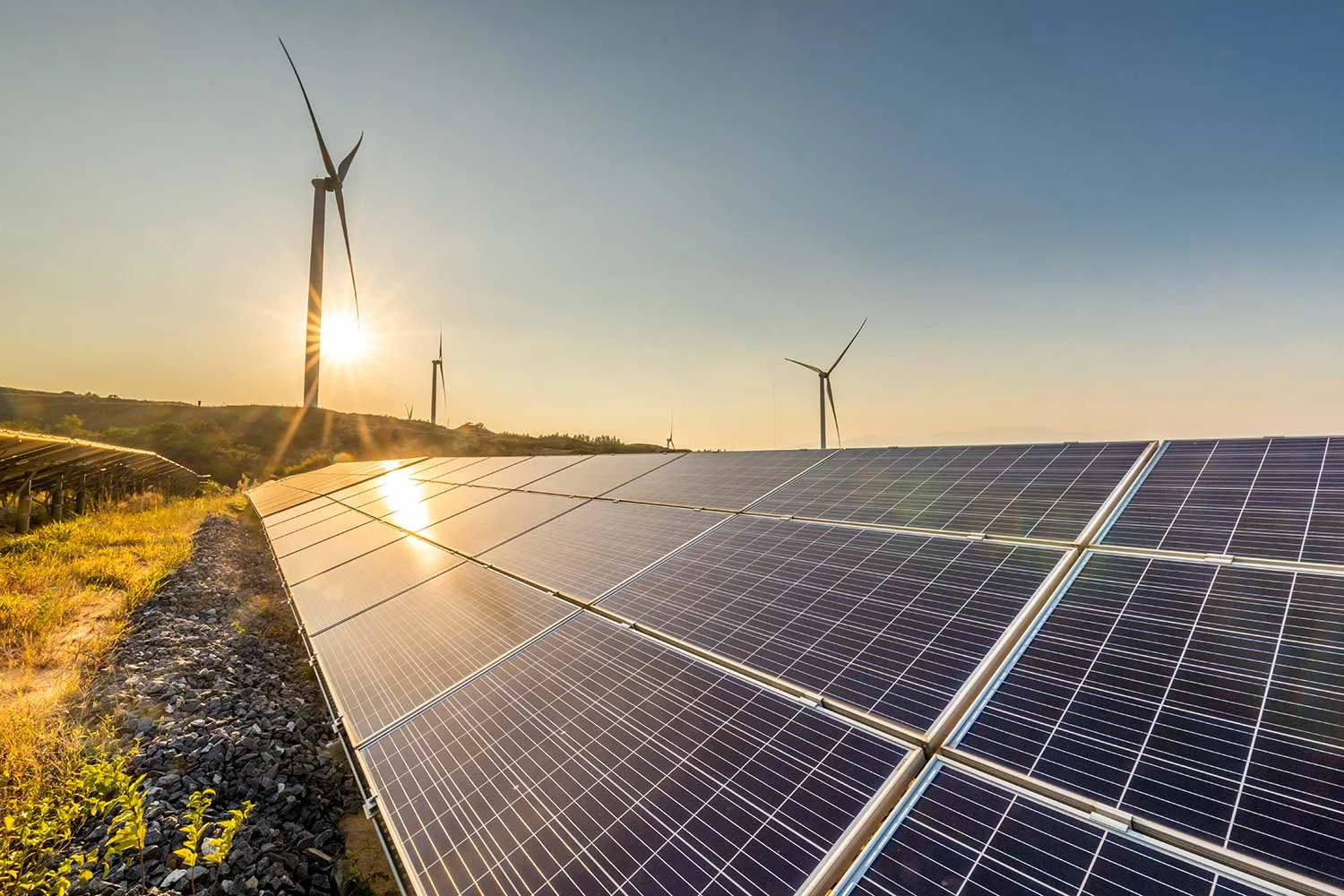 Foto einer Solaranlage mit Windrädern vorm Sonnenuntergang