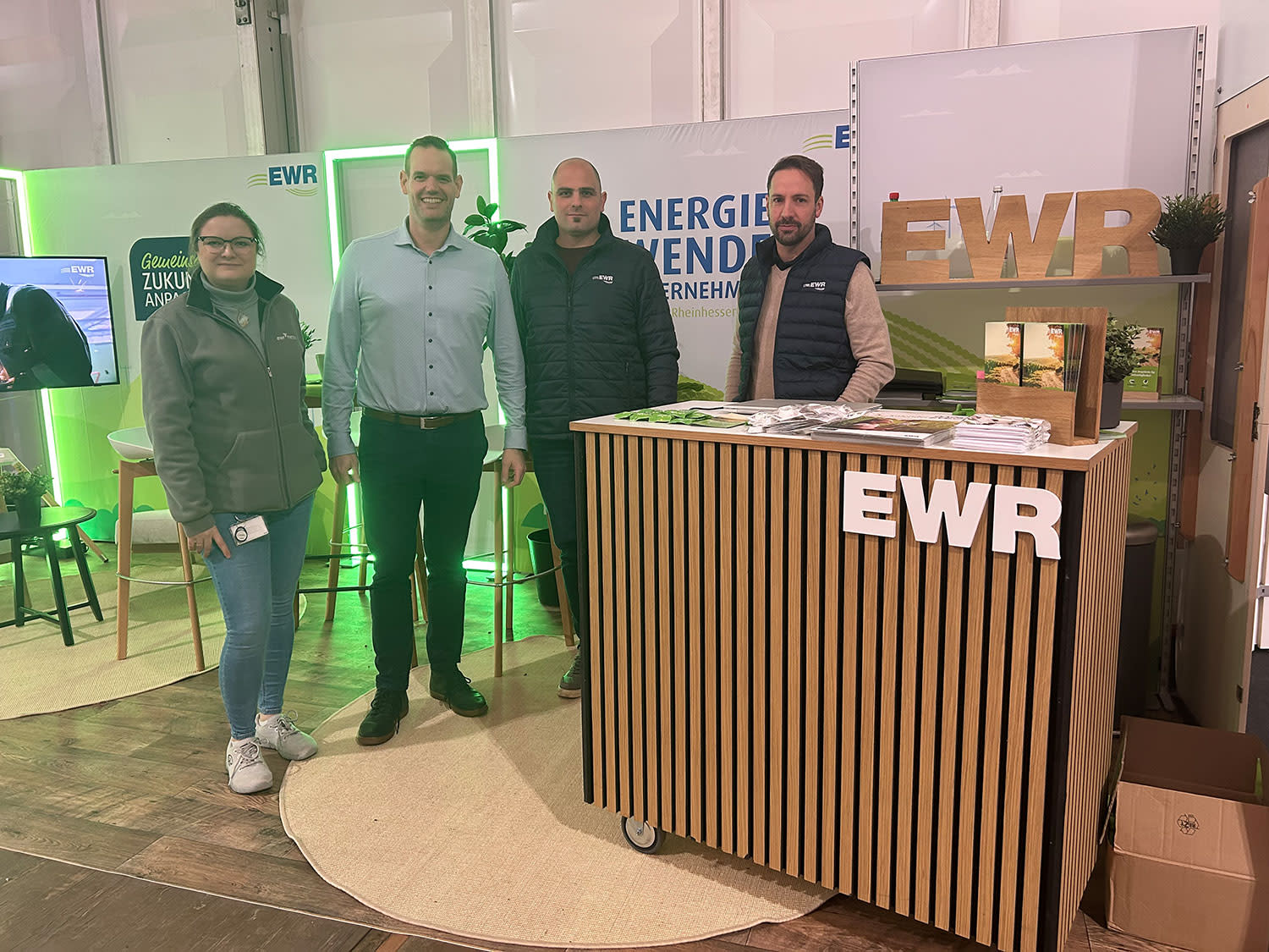 Vier Mitarbeiter stehen am EWR Messetand Vier Mitarbeiter stehen am EWR Messetand