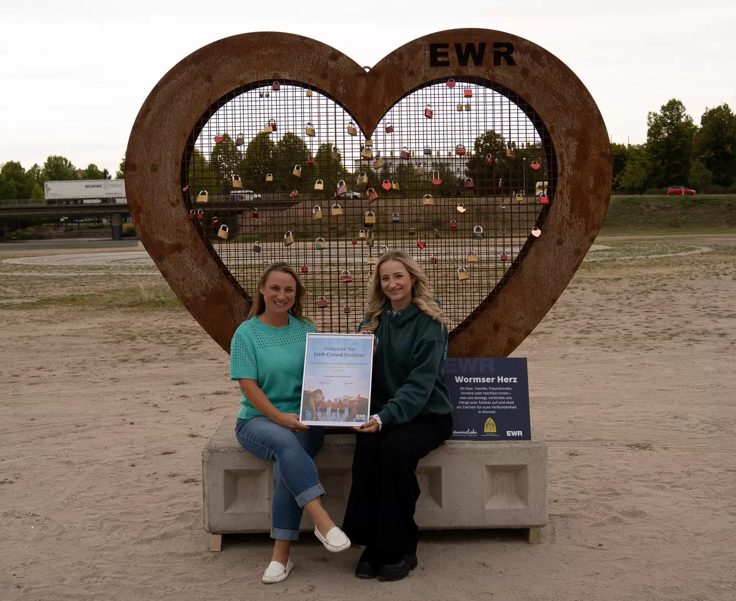 Zwei Frauen sitzen vor einem Metallherz