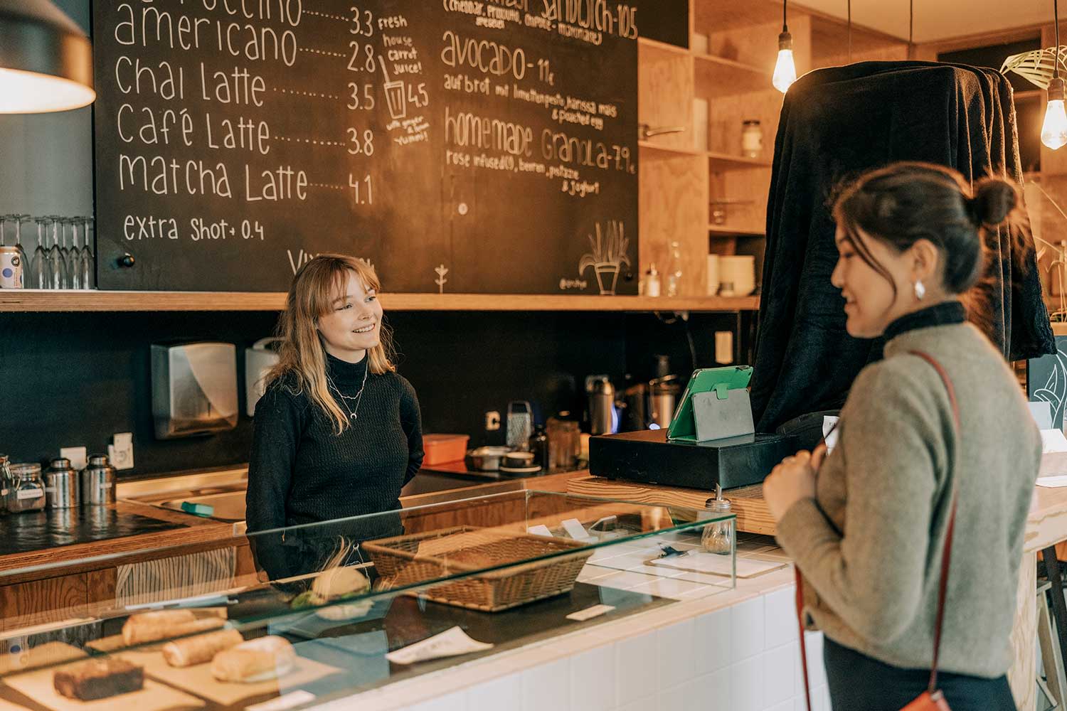 Kellnerin nimmt Bestellung von einer Kundin im Café entgegen