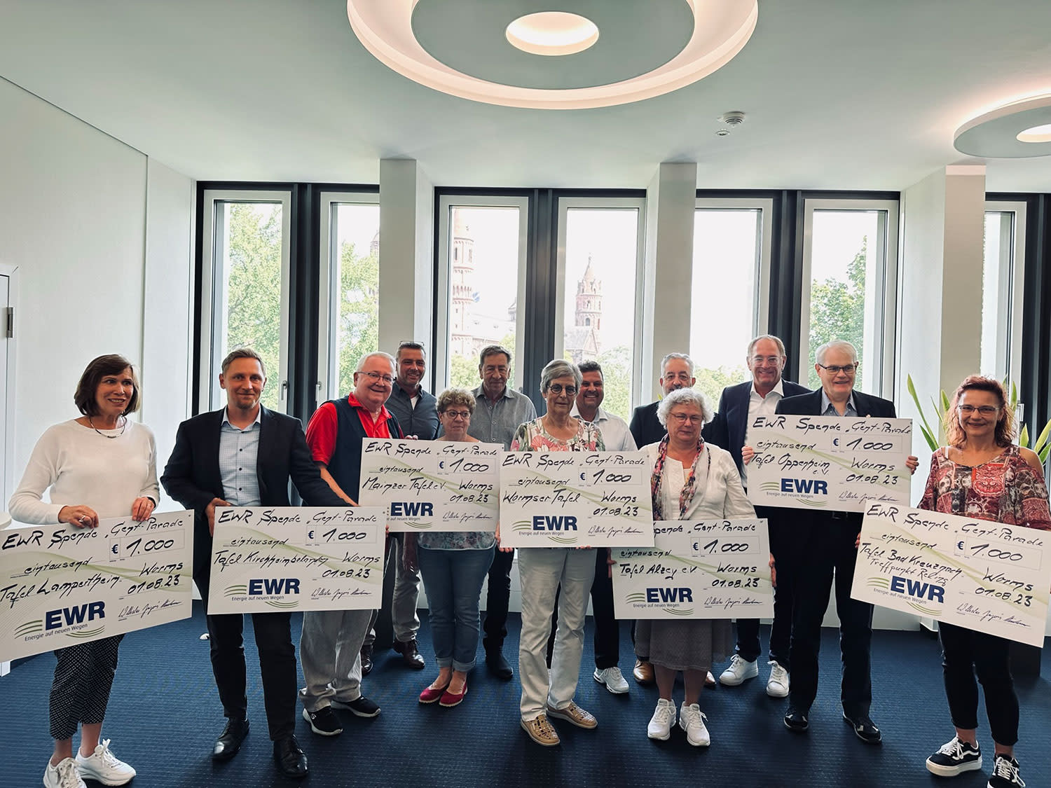 Mitarbeiter der Tafeln und der EWR AG stehen zusammen und halten symbolische Schecks in den Händen