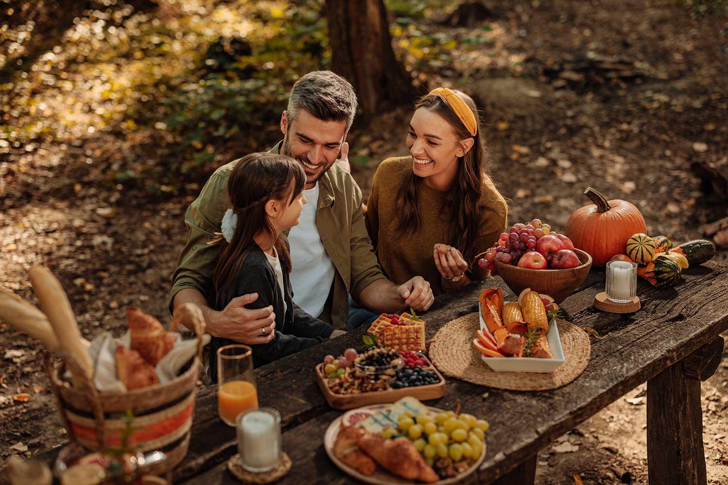 Mutter, Vater und ihre kleine Tochter beim Picknick im Wald