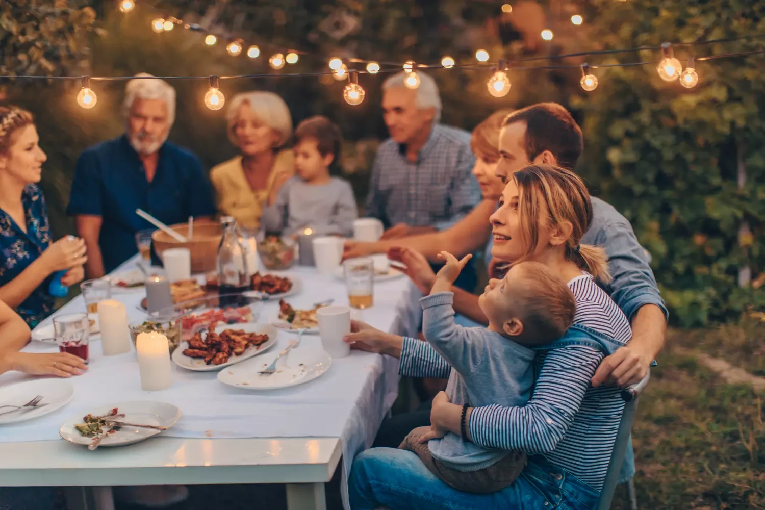Familie sitzt abends gemütlich am Gartentisch