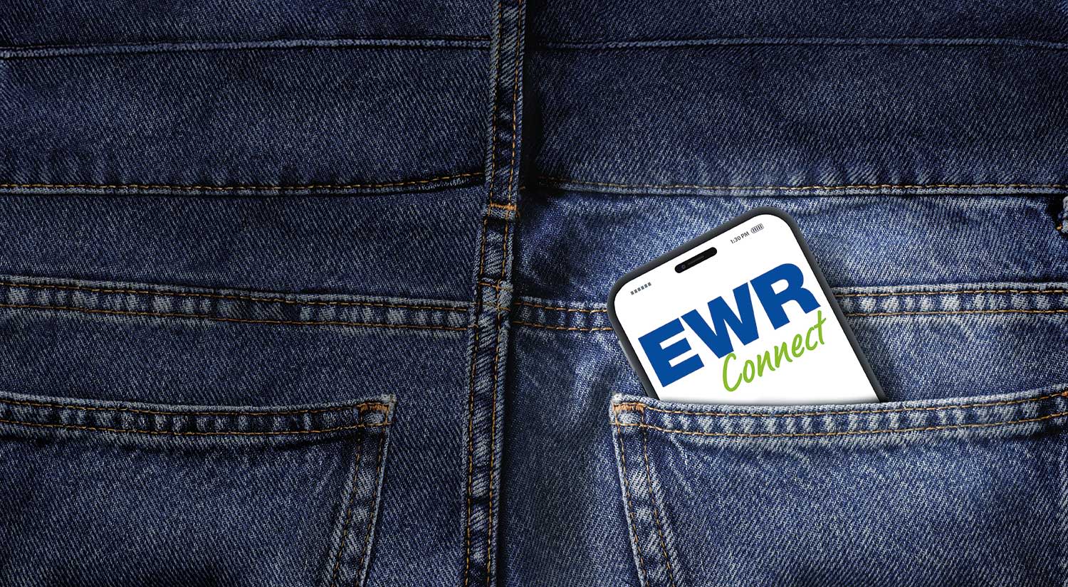 Ein Handy ist in einer Jeanshosentasche eingesteckt. Auf dem Bildschirm ist die EWR Connect App geöffnet