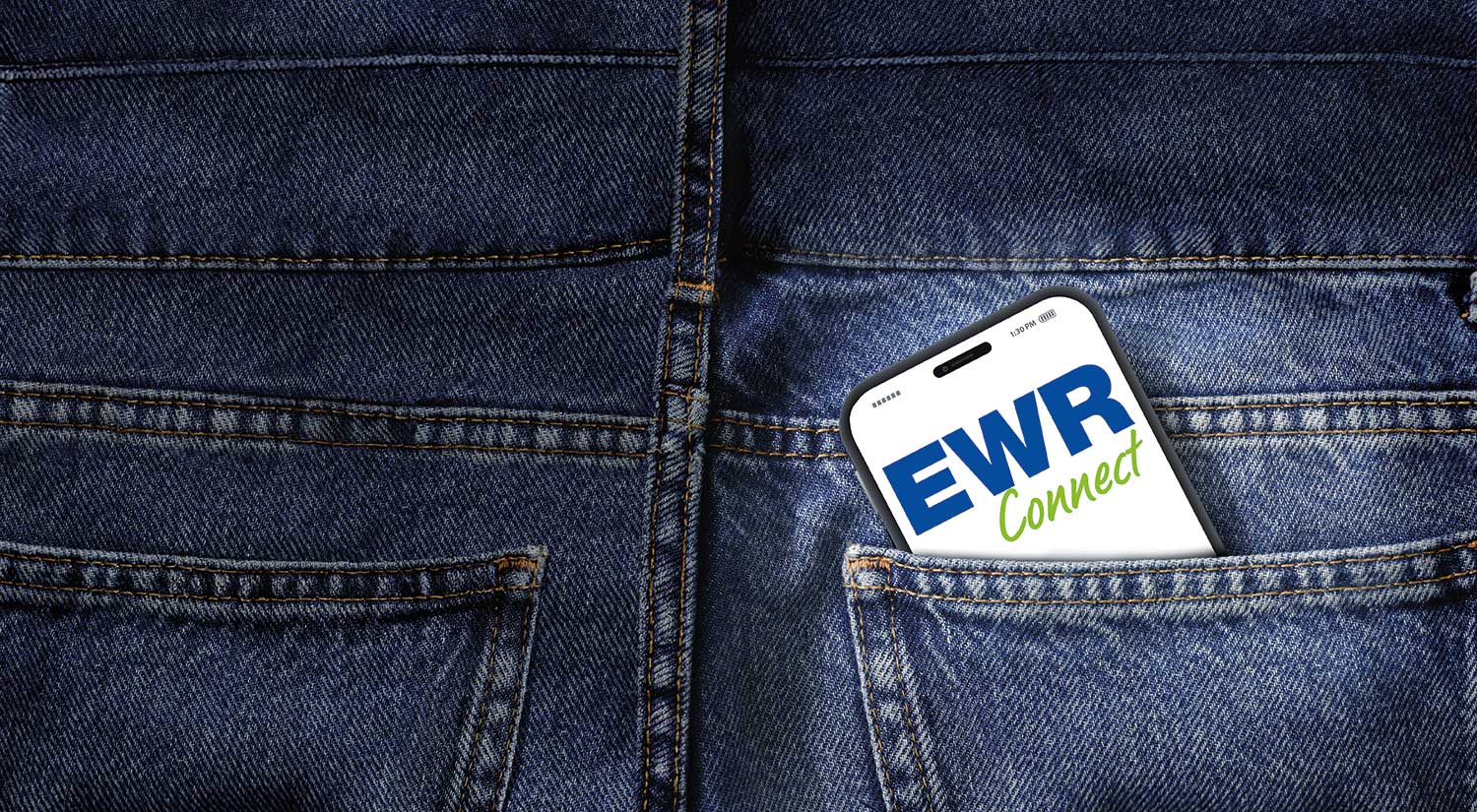 Ein Handy ist in einer Jeanshosentasche eingesteckt. Auf dem Bildschirm ist die EWR Connect App geöffnet