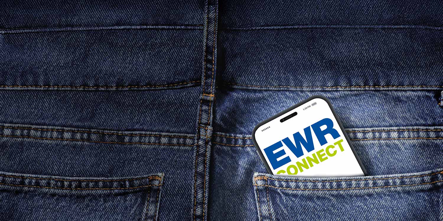 Ein Handy ist in einer Jeanshosentasche eingesteckt. Auf dem Bildschirm ist die EWR Connect App geöffnet