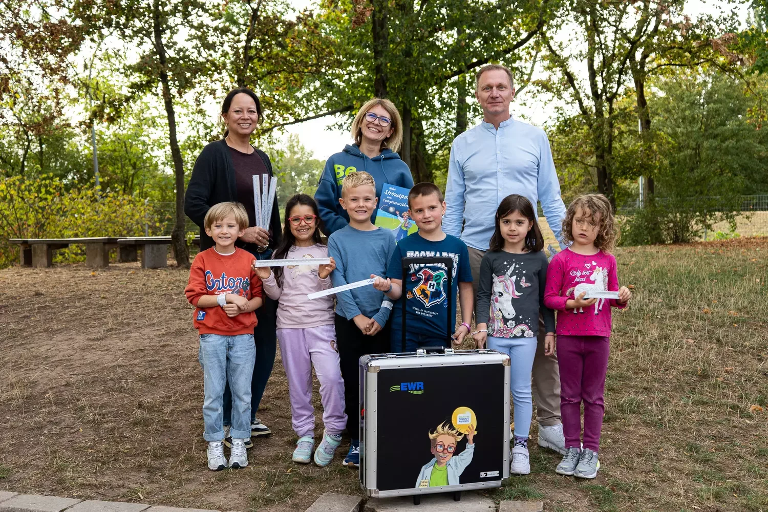 Erwachsene stehen mit Kinder vor dem EWR-Energiesparführerschein Erwachsene stehen mit Kinder vor dem EWR-Energiesparführerschein