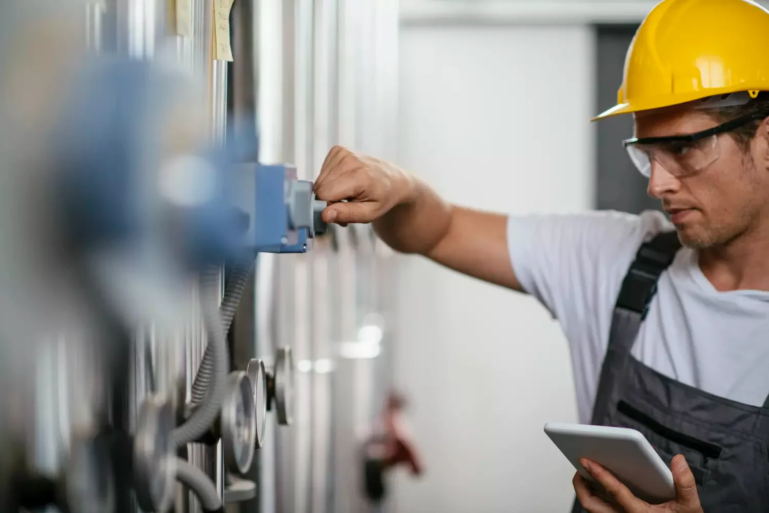 Handwerker mit Tablet an einer verarbeitenden Anlage.