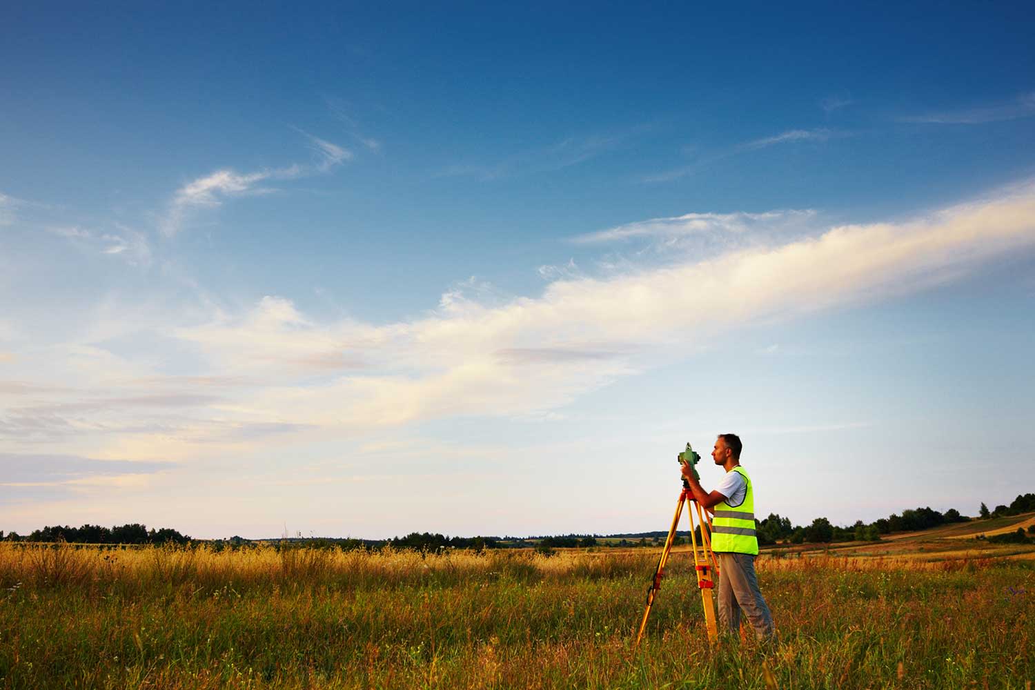 alt = #Vermessungstechniker steht auf einem Feld'