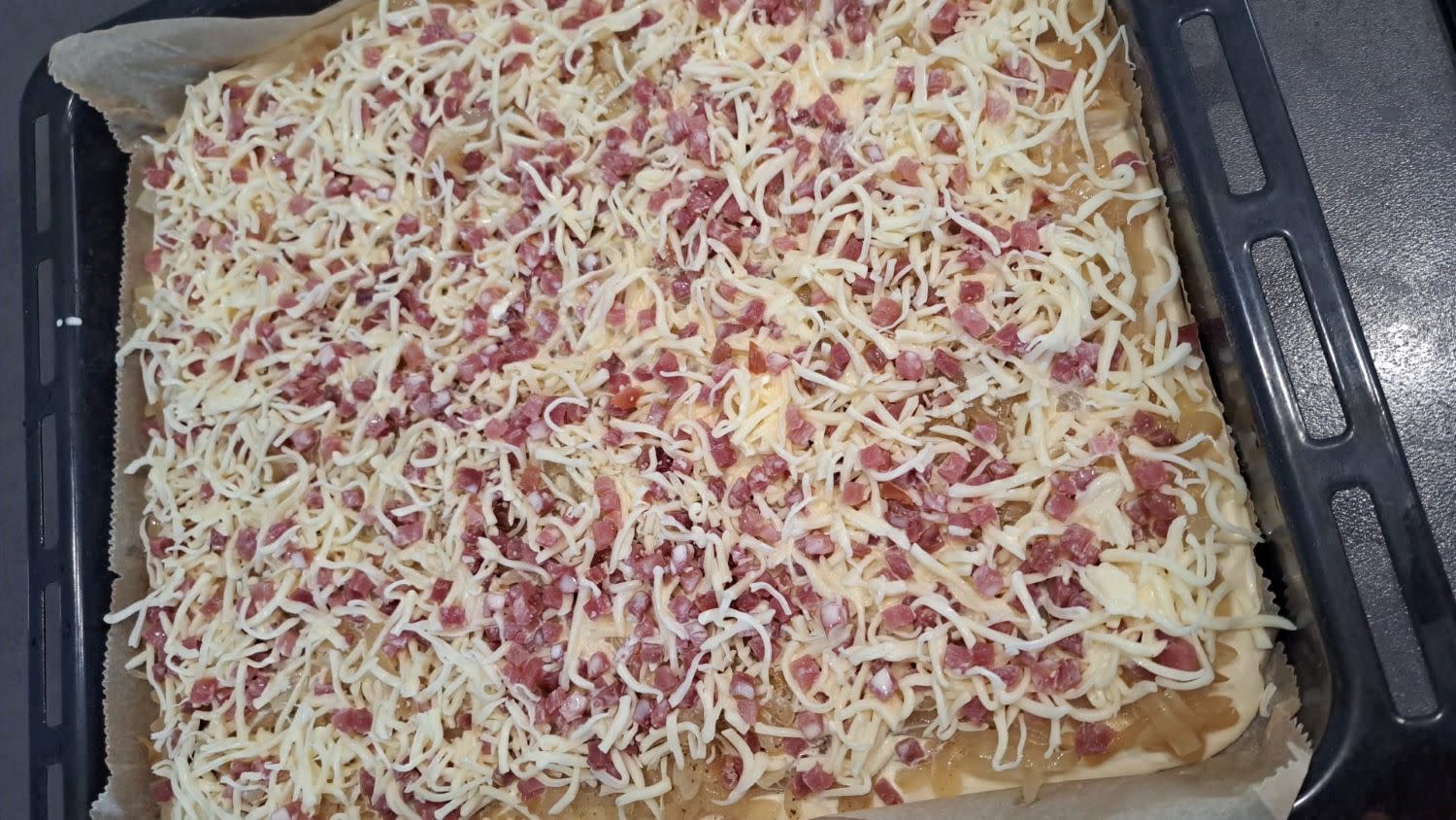 Zwiebelkuchen mit Speck und Käse belegt