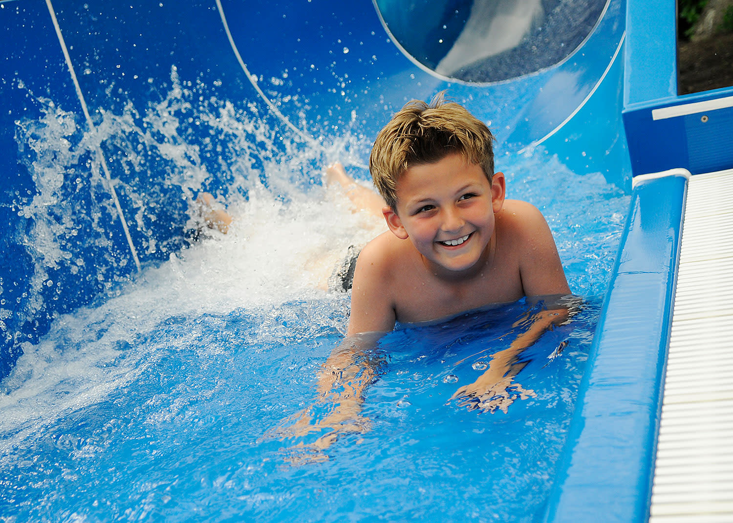 glücklicher Junge rutscht Wasserrutsche im Schwimmbad glücklicher Junge rutscht Wasserrutsche im Schwimmbad