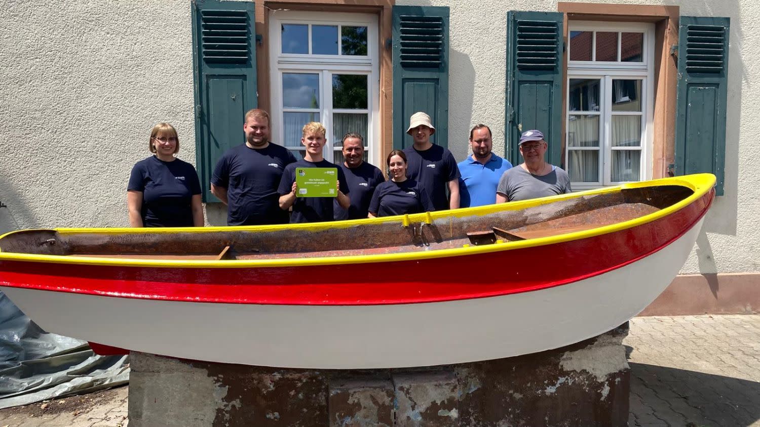Titelbild EWR-Mitarbeitende stehen vor einem frisch gestrichenem weiß-rotem Boot mit einem gelben Handlauf.