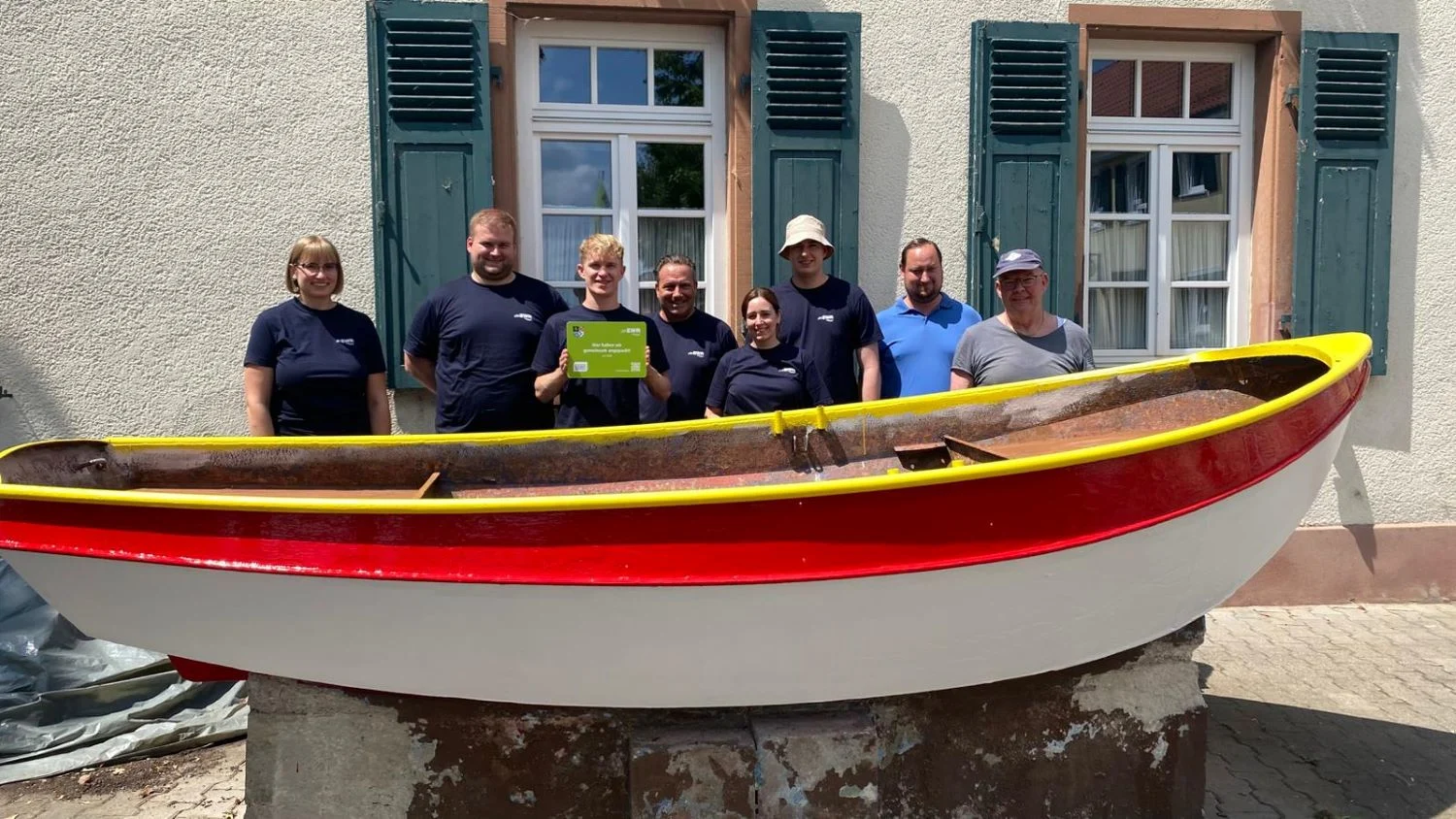 Titelbild EWR-Mitarbeitende stehen vor einem frisch gestrichenem weiß-rotem Boot mit einem gelben Handlauf.
