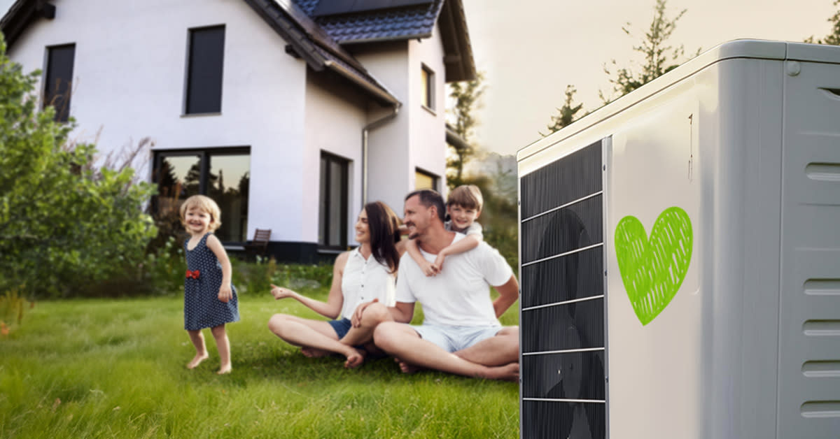 Eine Familie sitzt im Garten neben einer Wärmepumpe auf die ein Herz gemalt ist