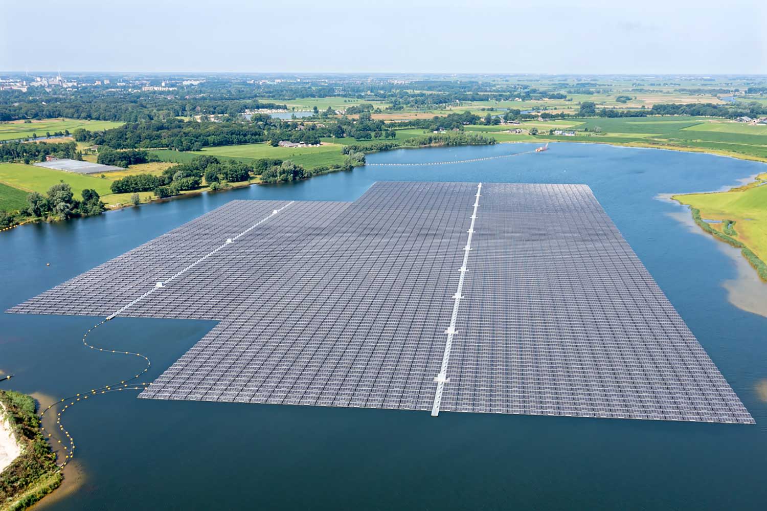 Titelbild Luftaufnahme von Sonnenkollektoren auf einem See auf dem Land