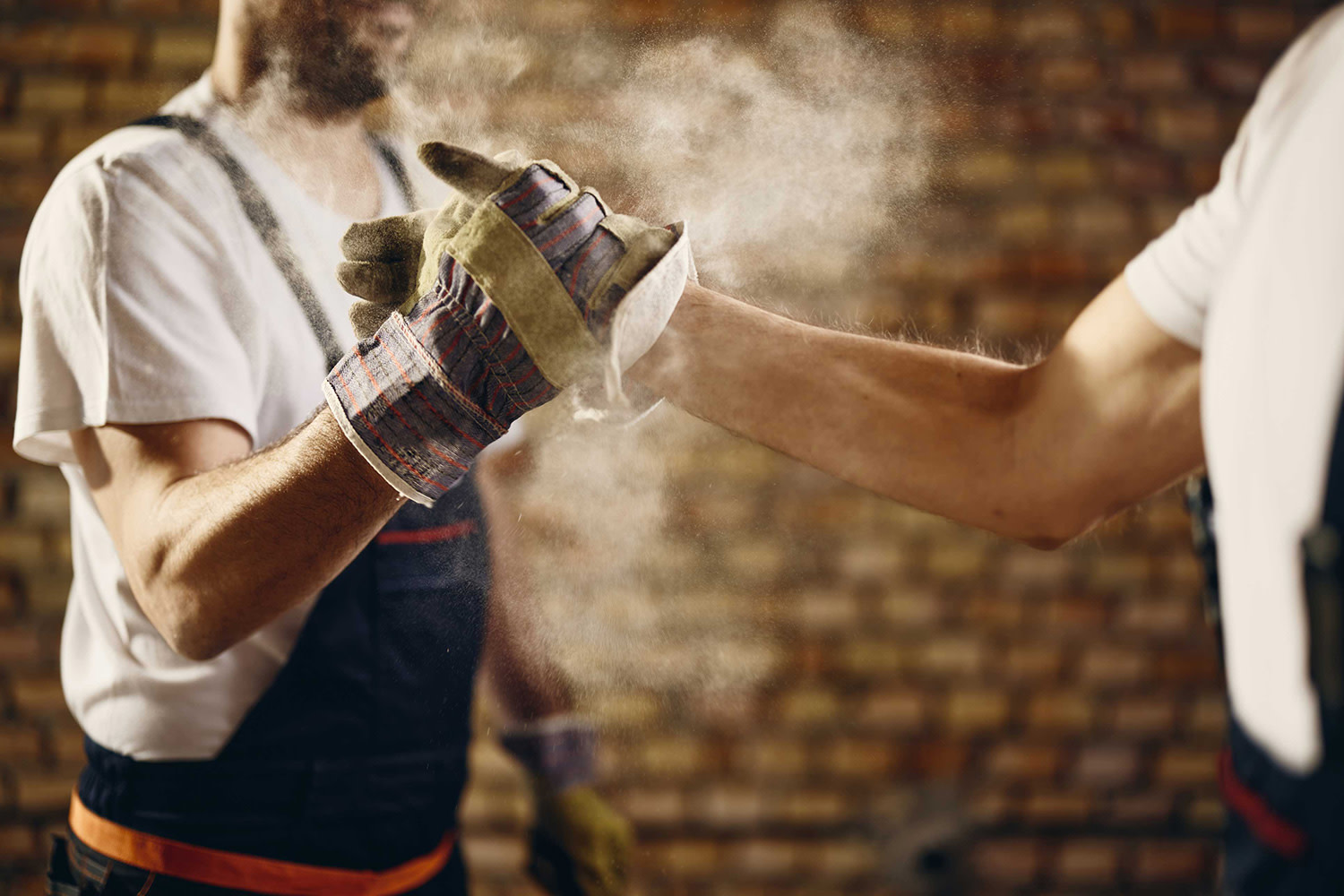 Zwei unkenntliche Bauarbeiter begrüßen sich per Handschlag