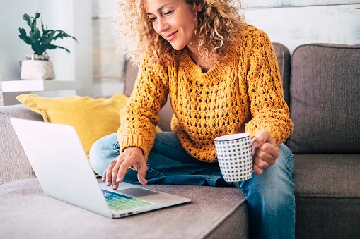Frau sitzt auf der Couch am Laptop