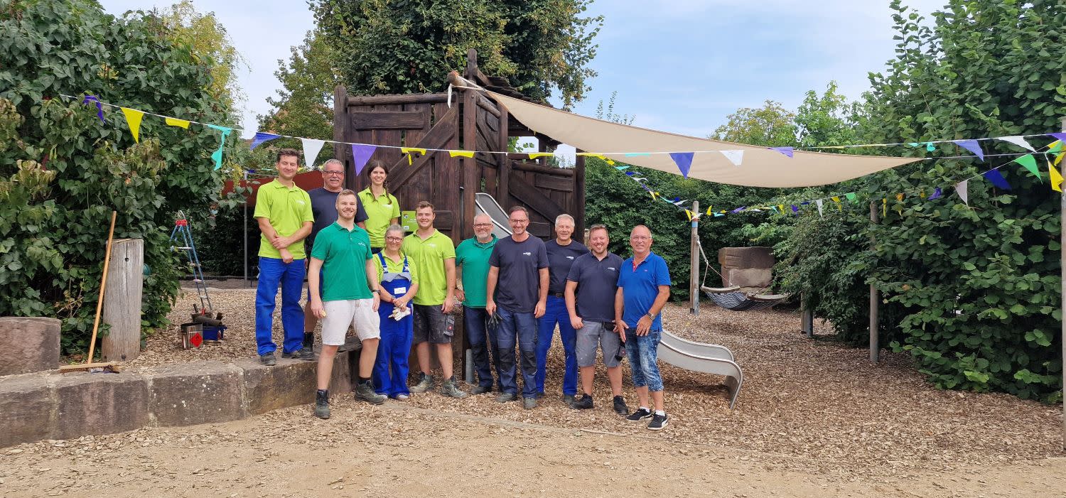 Titelbild Die stolzen Helferinnen und Helfer der EWR stehen vor dem fertiggestellten Spielplatz der Kindertagesstätte Regenbogen.
